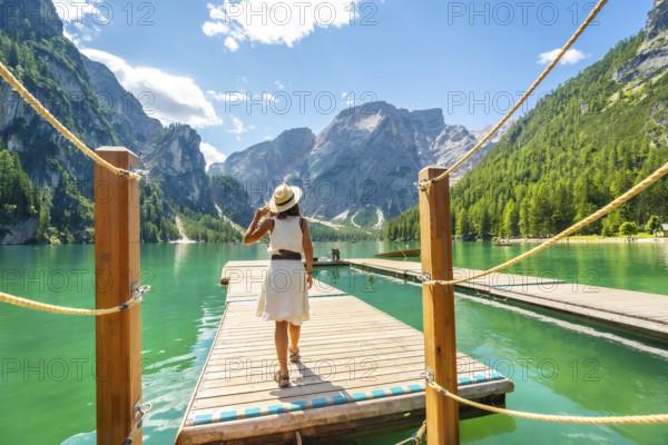 Woman walking along a wooden pier at lake braies, enjoying the turquoise waters and stunning