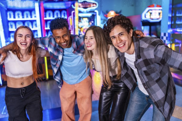 Four young cheerful multi ethnic friends are hugging each other, smiling and having fun together at