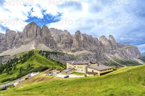 Green meadows and a mountain hotel are surrounded by the breathtaking peaks of the dolomites on a