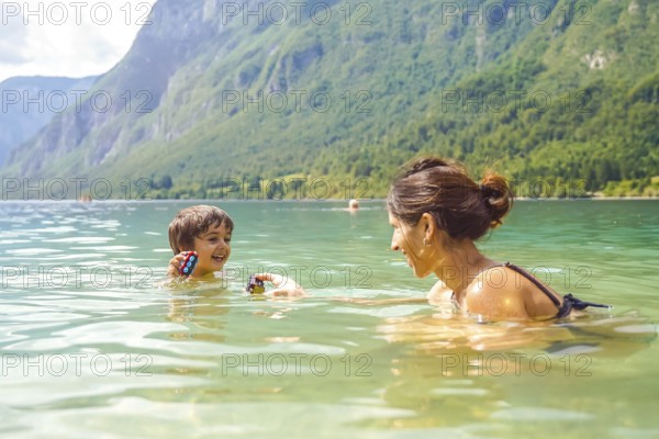 Mother and son enjoying summer fun, playing with toys while swimming in the refreshing waters of