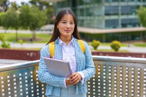 Three quarter length portrait of a beauty female asian student standing proud outside the
