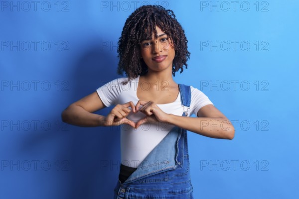 Studio portrait featuring a young woman forming a heart shape with her hands, radiating love and