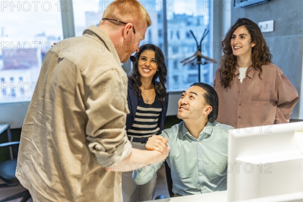 Business team congratulating their colleague on a successful project, shaking hands in the office