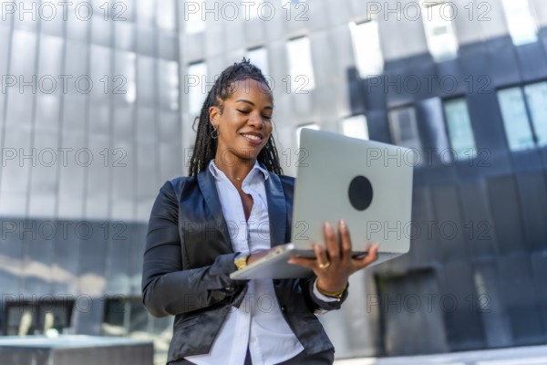 Portrait of a beauty confident latin businesswoman standing using laptop outside a financial