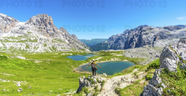 Tourist enjoying the scenic view of tre cime di lavaredo and alpine lakes on a sunny summer day in