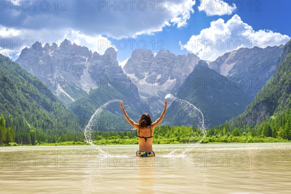 Young woman enjoying a refreshing swim in the scenic lago di landro, dolomites, italy, splashing