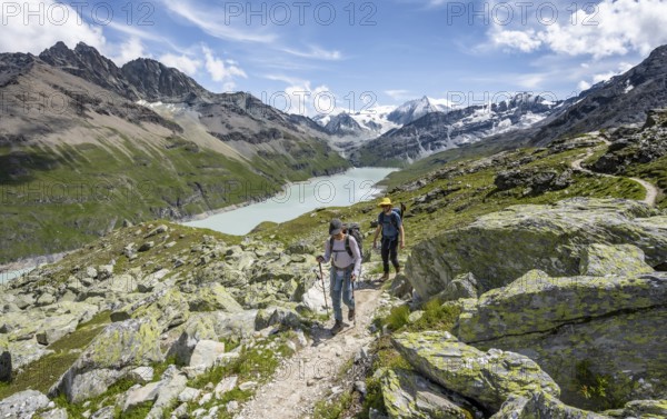 Two mountaineers on a hiking trail, view of a blue mountain lake, Lac des Dix reservoir, mountain