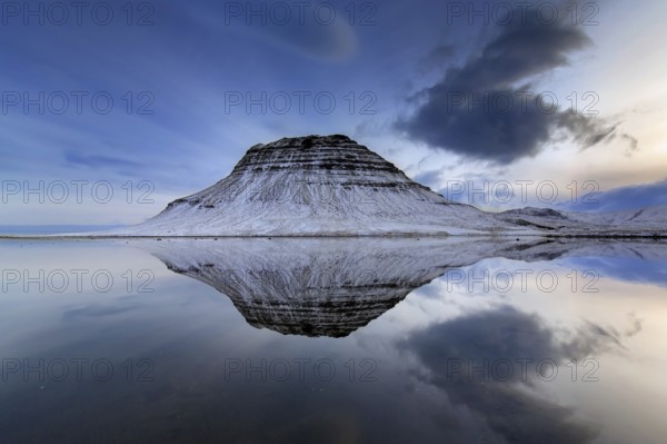 Kirkjufell, nunatak hill covered in snow reflected in water of fjord on the Snæfellsnes peninsula