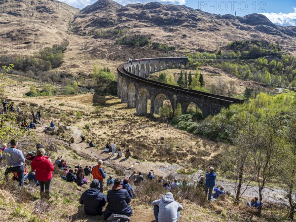 Tourists waiting for the jacobite steam train at the Glenfinnan viaduct, scottish highland,