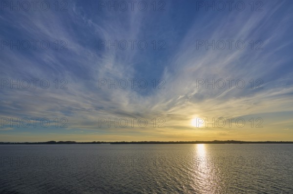 Sunrise over the calm sea, with wide sky and soft clouds in warm light, Bergen, Vestland, Norway,