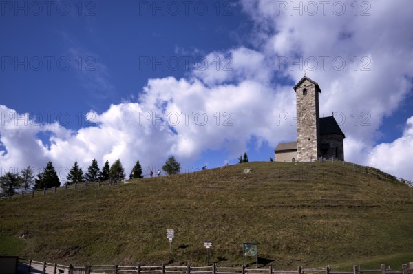 Hikers in front of St. Vigilius church, Vigilius on the yoke, faith trail, near Lana, South Tyrol,