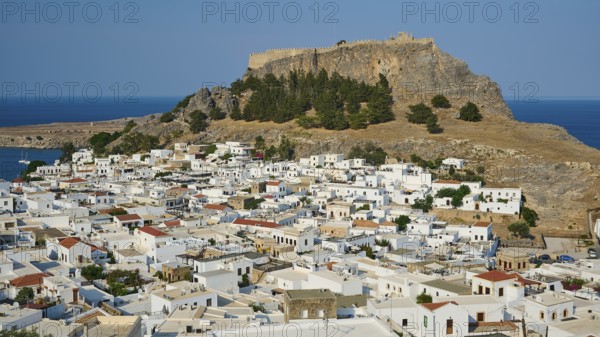 Clear daytime view of a coastal town with traditional Mediterranean architecture under a fortress,
