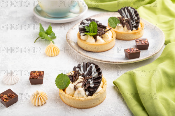 Sweet tartlets with chocolate and cheese cream with cup of coffee on a gray concrete background and