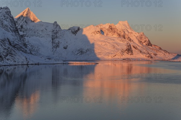 Snow-covered mountains reflected in the fjord at sunrise, winter, Reine, Moskenesoya, Lofoten,