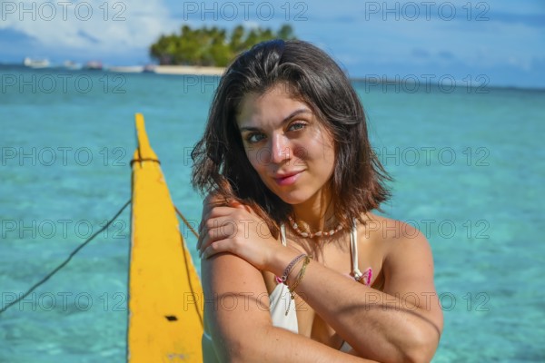 Young woman relaxing on traditional outrigger boat, enjoying the turquoise waters of daku island in