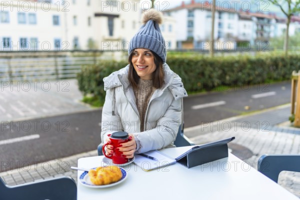 Beauty woman wearing warm clothes and woolly hat warming hands with hot coffee in a sidewalk