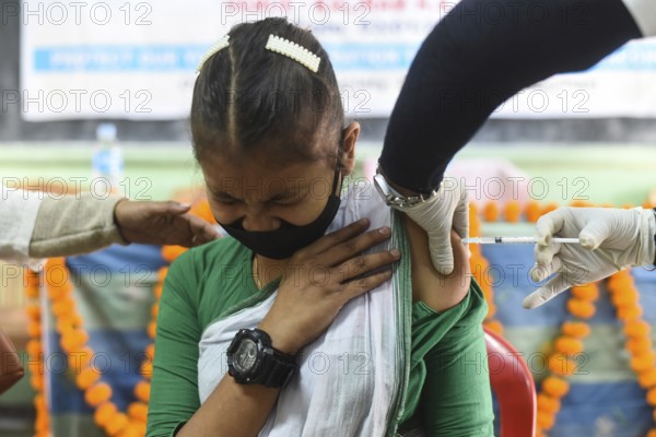 A health worker inoculates a student with a dose of a Covid-19 coronavirus vaccine during a