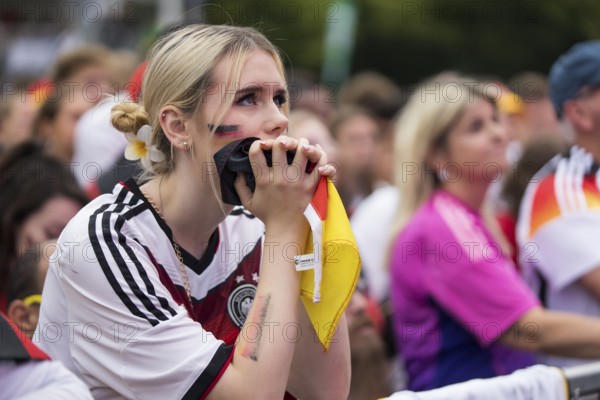 A woman watches the football match in the fan zone at the Brandenburg Tor during the quarter-final