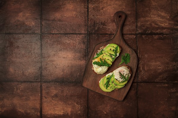 Sandwich with cream cheese, sliced avocado and boiled egg, arugula, on grainy bread, homemade,