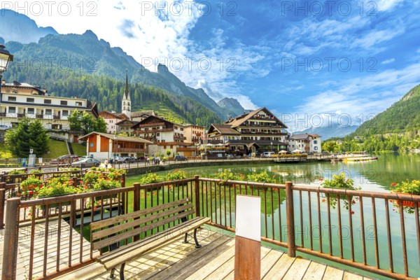 Tourists strolling along the picturesque shores of alleghe lake in the stunning dolomites on a