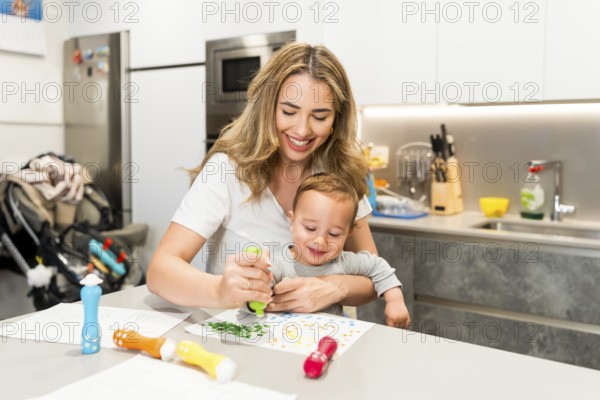 Happy mother and baby boy enjoying creative time together, painting with colorful markers in a
