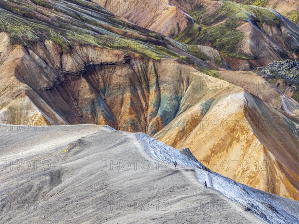 Hikers decending the slopes of Mt. Blahnukur, colorful rhyolite mountains, lava field,