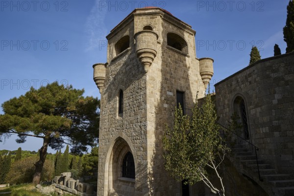 St John's Church, Historic stone tower with windows and stairs, surrounded by trees under a clear