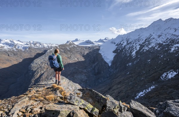 Mountaineer standing on a rock, surrounded by an impressive mountain landscape with snow-covered