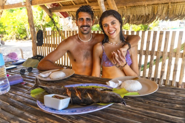Tourists embracing local cuisine during their vacation in the philippines, savoring a grilled fish