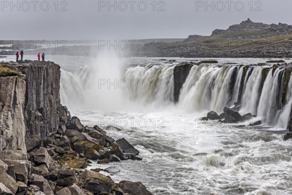 People standing in front of a waterfall at a river, cascades, spray, rapids, summer, foggy,