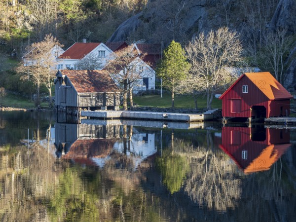 Fjord near Ana Sira at the norwegian southern coast, lonely houses at the foot of a rock formation,