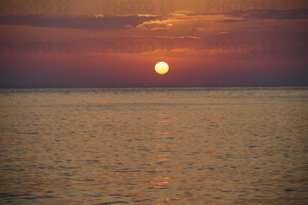 Sunset over the calm sea under an orange sky, Mandraki, Nisyros, Dodecanese, Greek Islands, Greece,