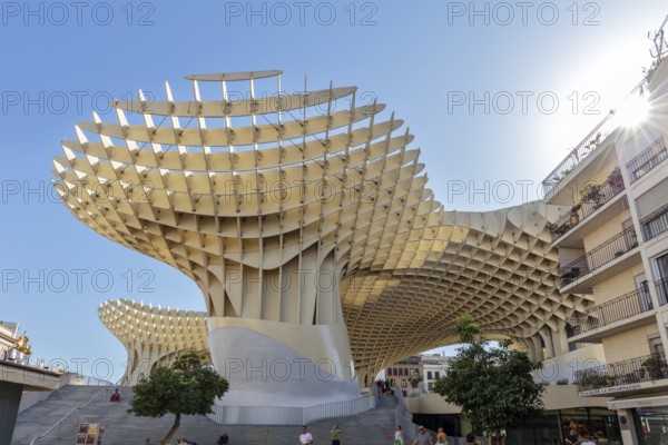 Imposing wooden construction of the Metropol Parasol in strong sunlight between city buildings,