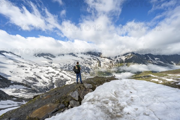 Mountaineer on hiking trail between snowfields, mountain landscape with summit Hoher Weißzint and