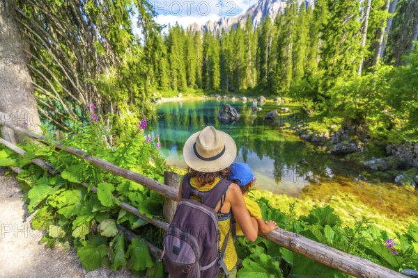Mother and child enjoying breathtaking view of lake carezza's turquoise waters, surrounded by lush