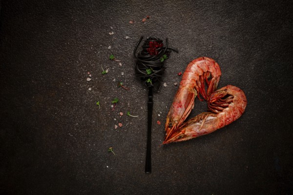 Black spaghetti, wrapped on a fork, langoustines in the shape of a heart, on the table, dish