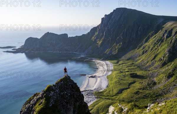 Climber on a rock, view of picturesque coastal landscape, steep coast with peak Måtind or Måtinden,