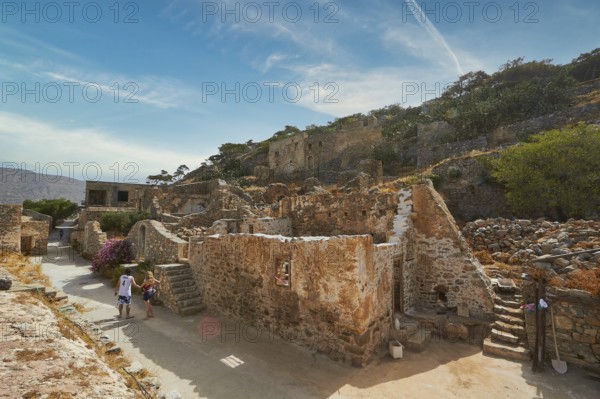 Tourists walking through an ancient village with ruins and pathways on a sunny day, Venetian Sea