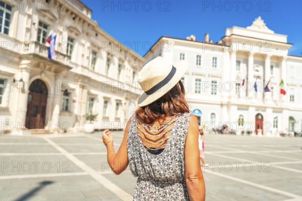 Woman tourist wearing straw hat walking in tartini square, piran, slovenia, enjoying summer