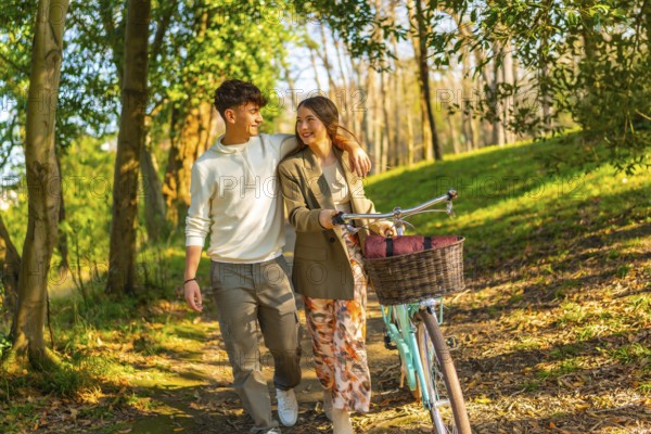 Happy young couple walking through a sunlit forest path with a vintage bicycle, embracing the