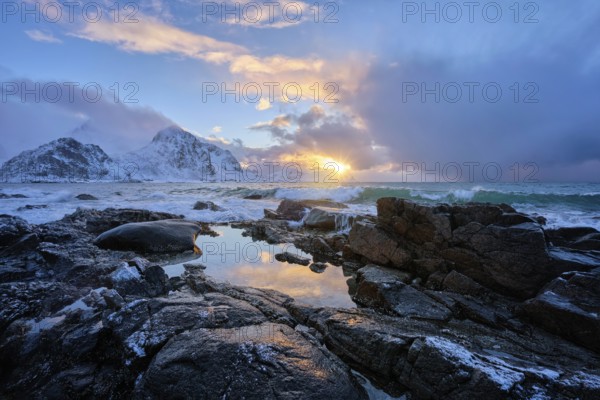 Beach of Norwegian sea on rocky coast in fjord on sunset in winter. Vareid beach, Lofoten islands,