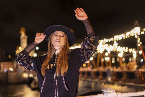Christmas lights in the city, Caucasian blonde girl dressed in black with a hat on an illuminated