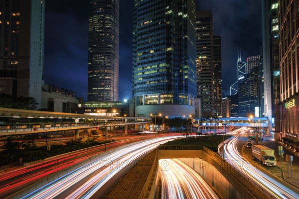 Street traffic in Hong Kong at night. Office skyscraper buildings and busy traffic on highway road