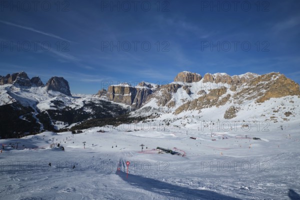 View of a ski resort piste with people skiing in Dolomites in Italy. Ski area Belvedere. Canazei,