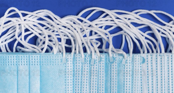 Close-up view of virus protection face mask with rubber ear straps on blue background as protection