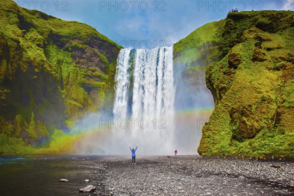 Grand waterfall in Iceland - Skogafoss. Picturesque huge rainbow appears in the water mist.