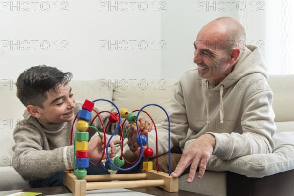Grandfather and grandson enjoying quality time together, playing with a colorful wooden bead maze