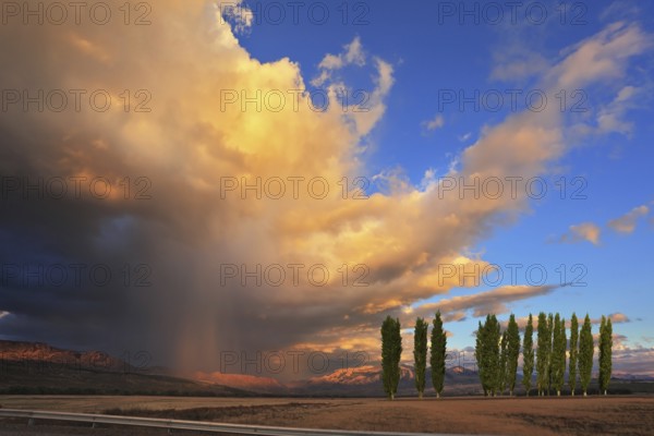 The beautiful huge cumulonimbus cloud is shined with the sunset. Rain streams are shone with orange