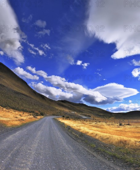 The dirt road in the Chile National Park Torres del Paine. Magic clouds incredible shapes formed by