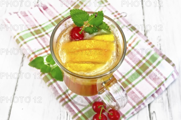 Lemonade in a wineglass with cherry, lemon and orange, mint on a napkin on a wooden plank